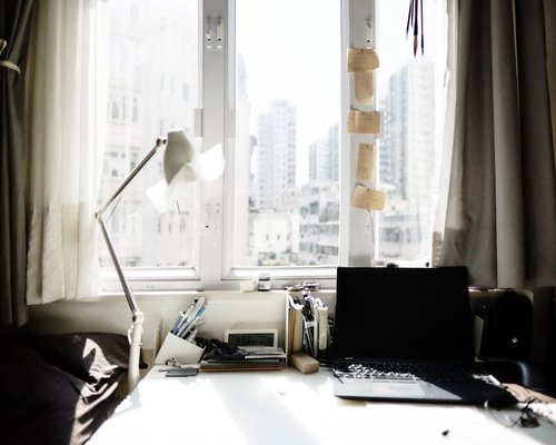 A well organized desk setup with natural sunlight streaming through a large window illuminating the space